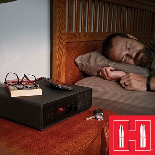 Man sleeping next to a digital clock on a bedside table with glasses, remote, and keys.
